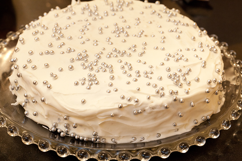 Een cake met wit glazuur en zilveren pareltjes ter decoratie